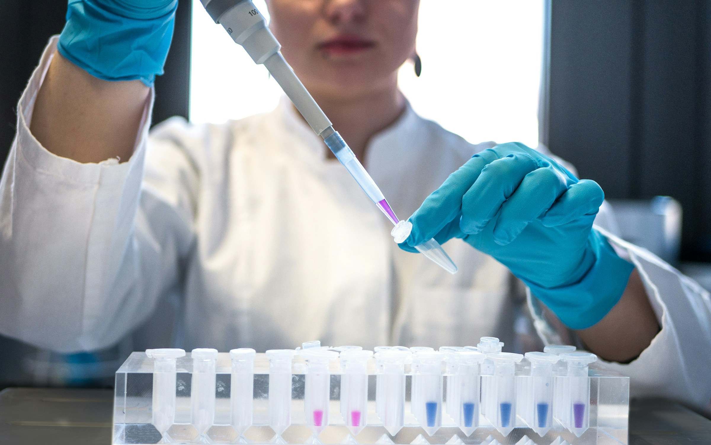 Profesional de laboratorio pipeteando muestras en tubos de ensayo
